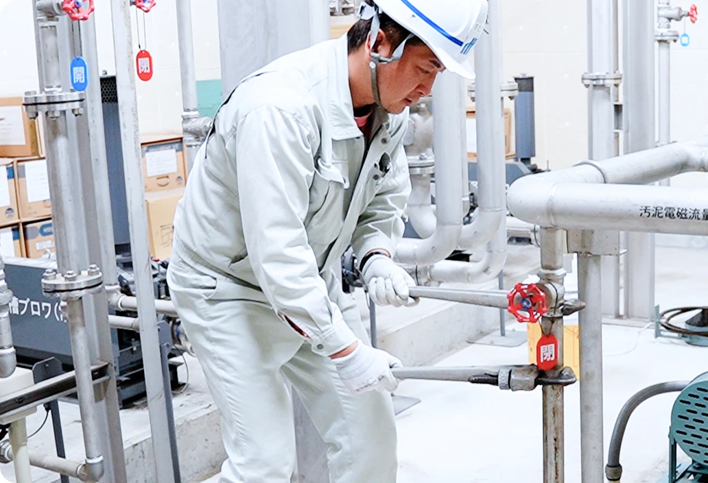 管理施設内の配管のバルブをレンチで締めている社員の写真